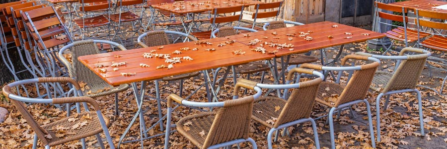 Außengastronomie im Herbst mit heruntergefallenem Laub auf den Tischen