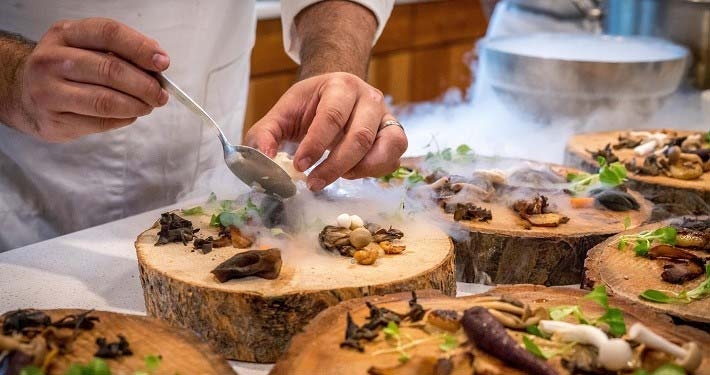 Koch platziert vorsichtig gefrorenes Essen auf einem Teller in Design einer Holzscheibe