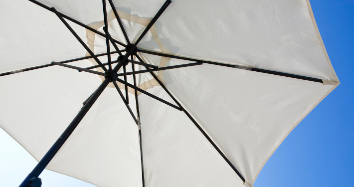 Sonnenschirm mit weißer Bespannung und Mast aus dunkelbraunem Holz