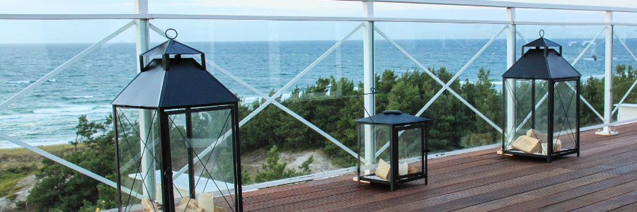 Restaurant-Terrasse mit Windschutzwänden aus Glas und Blick aufs Meer