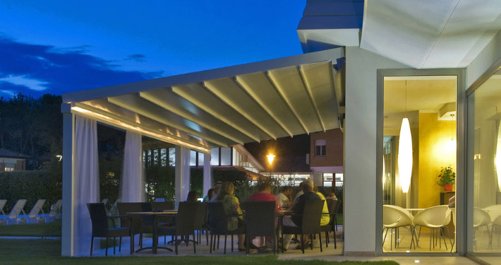 Gäste sitzen auf der Restaurant-Terrasse unter einer mit LEDs beleuchteten Pergola