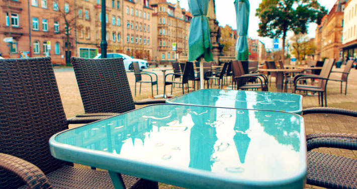 Ein paar regennasse Tische in der Außengastronomie einer Innenstadt