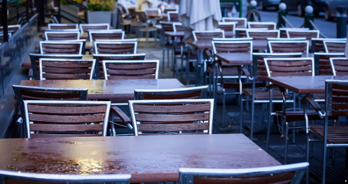 Eine Reihe Tische und Stühle einer Gastroterrasse nach dem Regen